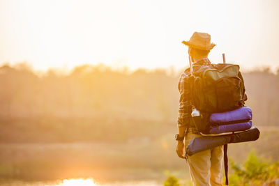 Rear view of man standing against sky during sunset