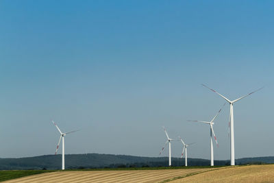 Wind turbines on field against clear sky