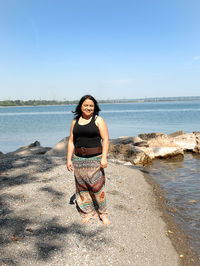 Portrait of woman standing at beach against clear sky