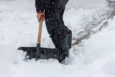 Low section of person standing on snow covered landscape