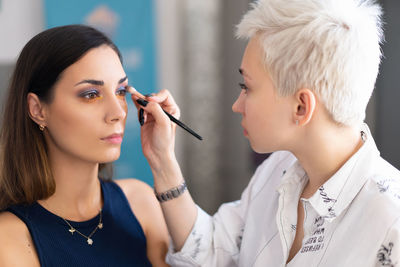 Beautician applying make-up to fashion model in studio