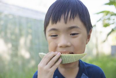 Close-up of boy eating melon outdoors