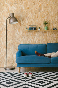 Crop businesswoman with shoes off chilling on blue soft couch during workday enjoying break