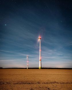 Wind turbines on field against sky at night