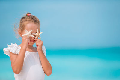 Portrait of boy holding blue sea against sky