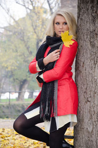 Beautiful young woman with arms raised in tree