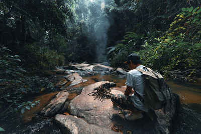 Rear view of man against waterfall in forest