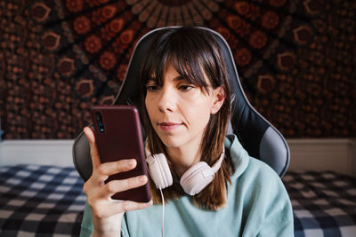 Young woman using mobile phone on chair