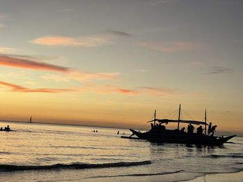 Silhouette sailboat in sea against sky during sunset