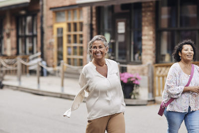 Smiling disabled woman strolling with female friend while walking at street