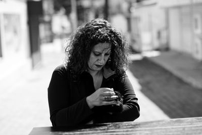 Young woman looking away while sitting on mobile phone