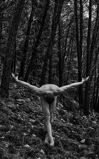 Naked man bending in forest