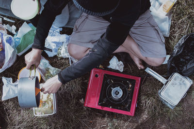 Low section of man making food while sitting on field in forest