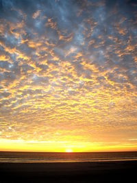 Scenic view of sea against dramatic sky during sunset