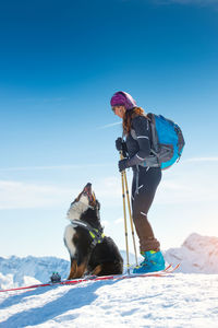 Person with dog on snow against sky