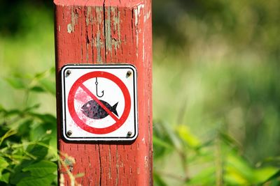 Close-up of warning sign on wooden post