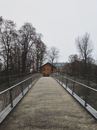 Street amidst bare trees and building against sky