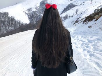 Rear view of woman standing on snow covered landscape