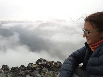 Young woman on cliff at geirangerfjord against cloudy sky