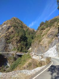 Road by mountain against blue sky