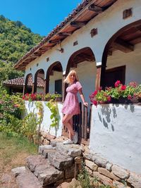 A young woman stands in front of the country house