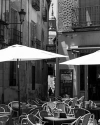 Empty chairs and tables in cafe amidst buildings in city