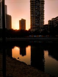 Reflection of silhouette buildings in city during sunset