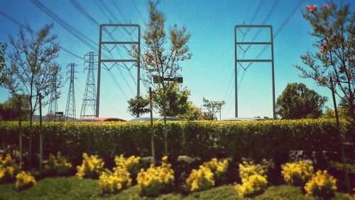 Power line on field against cloudy sky