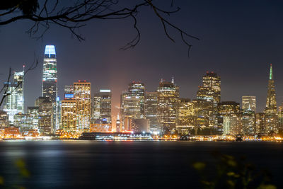 Illuminated buildings in city against sky at night