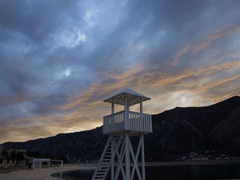 Hut by mountain against sky during sunset