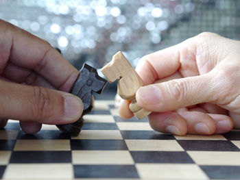 Cropped hands of person holding knights on chess board 