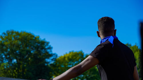 Rear view of man standing against blue sky