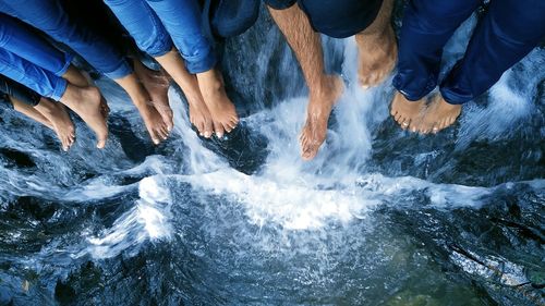 Low section of people sitting on rock at waterfall