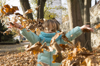 Girl playing with autumn leaves at public park