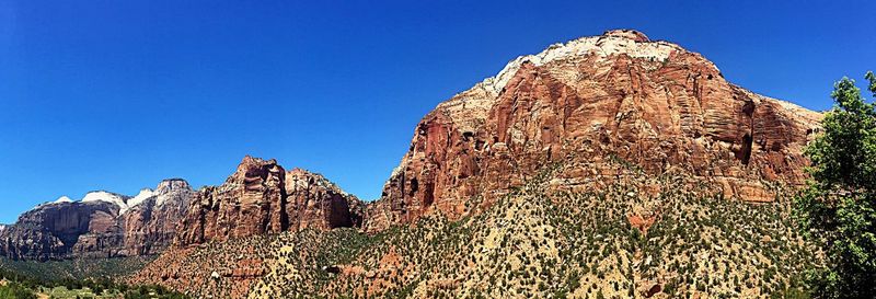 Low angle view of rocky mountain against clear blue sky