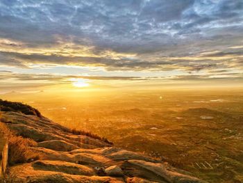 Scenic view of landscape against dramatic sky during sunset