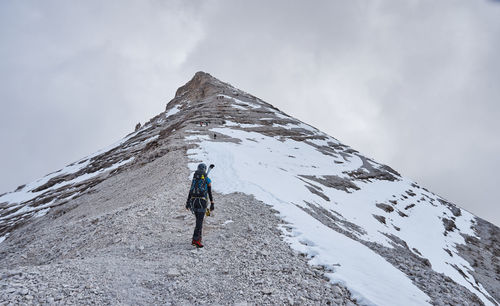 Rear view of person on snowcapped mountain against sky