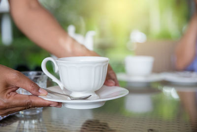 Midsection of woman holding coffee cup on table