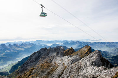 Overhead cable car over mountains against sky