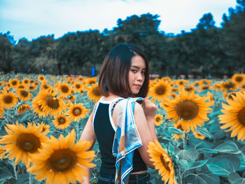 Portrait of woman standing amidst flowering sunflowers