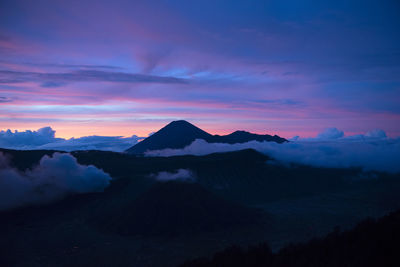 Scenic view of mountains against dramatic sky at sunset