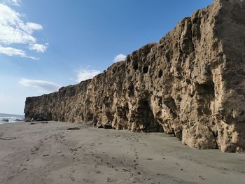 Rock formations on beach against sky