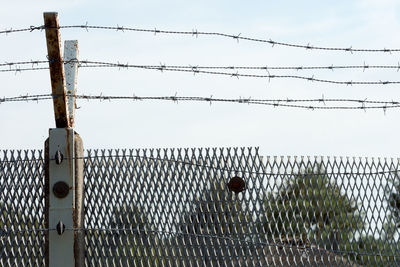 Low angle view of chain on chainlink fence against sky