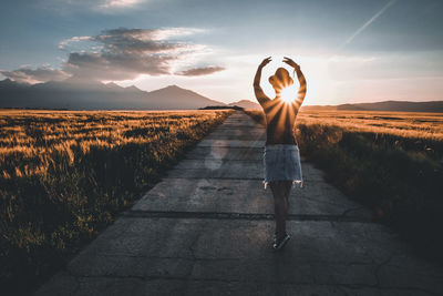 Woman standing on footpath at sunset