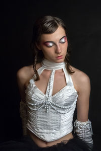 Portrait of beautiful young woman against black background