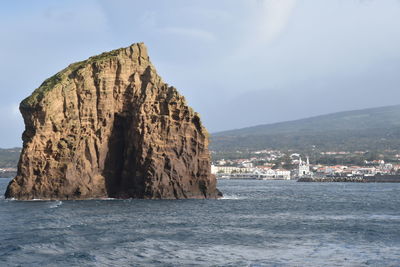 Rock formation in sea against sky