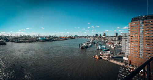 High angle view of harbor by city against blue sky