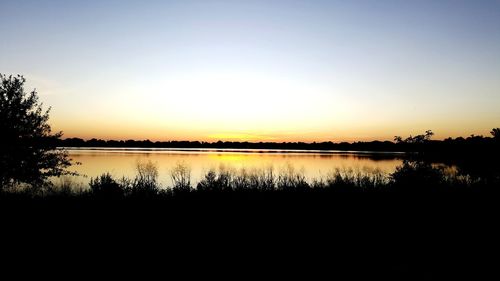 Scenic view of lake against clear sky during sunset