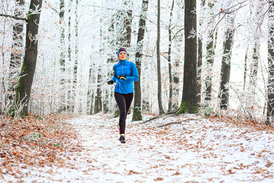 Portrait of woman jogging in forest during winter