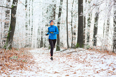 Full length of man running on road in forest